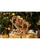 A wooden 3D puzzle of a marble run is displayed in front of a decorated Christmas tree. Podgląd zdjęcia produktu