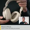 A person holding headphones with a picture-in-picture inset of a woman speaking. Produktbild-Vorschau
