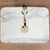 A top-down view of a white marble sink with a gold faucet. Podgląd zdjęcia produktu