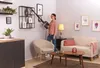 A woman is vacuuming a shelf in a living room. Voir les images du produit