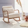 A cream boucle rocking chair with wooden arms and legs is placed on a white wooden floor, near a window with natural light. Decorative dried plants in vases are placed on the side. Anteprima dell’immagine prodotto
