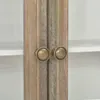 A close-up view of two brass knobs on a wooden cabinet door. Anteprima dell’immagine prodotto