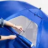 A person's hands are shown adjusting a tie on a blue umbrella or beach tent. Anteprima dell’immagine prodotto