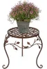 A potted plant with pink flowers sits on a decorative metal plant stand. Produktbild-Vorschau
