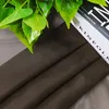 A close-up view of a brown fabric with green leaves and books in the background. Produktbild-Vorschau