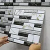 Hände, die eine schwarz-weiß-graue Marmor-Nachbildung abziehbare Wandfliese auf eine hellgraue Wand auftragen Voir les images du produit