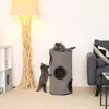 Two cats playing on a cat tree next to a floor lamp and a sofa. Produktbild-Vorschau