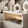 A close-up view of a modern nightstand with decorative vases and a book. Produktbild-Vorschau