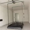 A garage with a roof-mounted lift system holding a black roof box. Produktbild-Vorschau