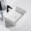 A white ceramic vessel sink with a black faucet is shown from a high angle on a white surface. Podgląd zdjęcia produktu