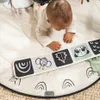 A baby is playing on a black and white themed playmat. Produktbild-Vorschau
