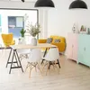 A bright and modern living or dining area with a yellow sofa, a wooden table with white chairs, and colorful storage cabinets. Podgląd zdjęcia produktu