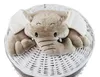 A plush elephant toy peeking out of a white wicker laundry basket. Podgląd zdjęcia produktu