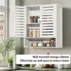A white wall-mounted storage cabinet with louvered doors, filled with various jars of food items. The cabinet is mounted on a light gray wall above a green marble countertop. Podgląd zdjęcia produktu