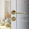 A close-up of a bronze door handle set on a white door, with a blurred background of a room interior. Produktbild-Vorschau