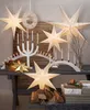 A festive Christmas display with illuminated paper stars, candles, and gifts on a wooden table. Podgląd zdjęcia produktu