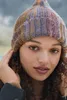 A close-up portrait of a woman wearing a knitted hat. Produktbild-Vorschau