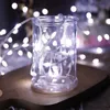 A close-up of a glass jar filled with white LED string lights, resting on a wooden surface. Produktbild-Vorschau
