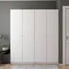 A white, four-door wardrobe is shown in a room with patterned wallpaper and a rug on the floor. Náhled obrázku produktu