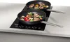 Two frying pans with food cooking on an induction cooktop. Podgląd zdjęcia produktu
