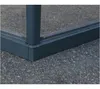 A close-up view of the corner of a grey aluminum greenhouse frame with glass panels, resting on an asphalt surface. Produktbild-Vorschau
