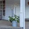 Two spherical LED light decorations are placed in a planter filled with white and purple flowers on a porch. Produktbild-Vorschau
