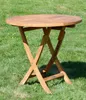 A round wooden folding table is placed on a grassy lawn. Produktbild-Vorschau