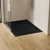 A black shower tray is installed in a bathroom with a glass shower enclosure and light wood flooring. Náhľad obrázku produktu