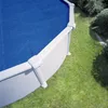 A round swimming pool with a blue solar cover, situated on a grassy lawn. Produktbild-Vorschau
