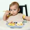 A baby sitting in a high chair eating from a divided plate. Produktbild-Vorschau