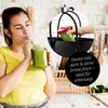 A young woman drinks a green smoothie from a mason jar while a blender jar is placed in a black tote bag. Produktbild-Vorschau