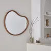 A mirror is mounted on a light gray wall, with a shelf below holding decorative items and a small lamp. Anteprima dell’immagine prodotto