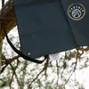A black fabric product hanging from a tree branch. Produktbild-Vorschau