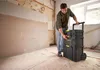 A man is interacting with a modular rolling toolbox in a room under renovation. Voir les images du produit