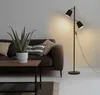 A modern living room scene with a brown sofa, a coffee table with a plant, and a black and gold floor lamp. Náhled obrázku produktu
