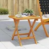 A wooden side table with a glass of water and a magazine on it, placed on a patio next to a chair. Produktbild-Vorschau