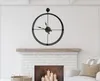 A black metal wall clock is mounted on a white wall above a fireplace. Podgląd zdjęcia produktu
