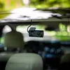 A dashcam is mounted on the inside of a car's rear window, with the interior of the car visible in the foreground and a blurred outdoor scene visible through the window. Produktbild-Vorschau