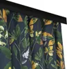 A close-up view of a dark blue curtain with a floral pattern of green and yellow leaves and white flowers. Produktbild-Vorschau