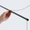 A hand is holding a gray drying rod with a black string attached. Produktbild-Vorschau