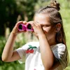 A young girl looking through pink binoculars outdoors. Produktbild-Vorschau