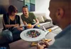 Three people are in a living room setting, with two of them looking at a tablet and a model of the Starship Enterprise on a coffee table. Podgląd zdjęcia produktu