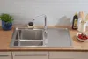 A stainless steel kitchen sink with a faucet, a sponge, a bottle of olive oil, and a bowl of cherry tomatoes on a wooden countertop. Produktbild-Vorschau