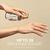 A person is applying hair oil to their hand from a bottle. Produktbild-Vorschau