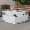 A modern living room with a white coffee table in the center, illuminated by blue LED lights. The table has multiple storage compartments and is adorned with books and a cup. Podgląd zdjęcia produktu