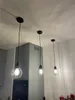 Three black pendant lights hanging from a ceiling in a kitchen or dining area. Produktbild-Vorschau