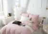 A neatly made bed with pink satin bedding, decorated with pillows and a throw blanket, in a bright, modern bedroom setting. Podgląd zdjęcia produktu