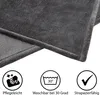 Close-up of a gray blanket with icons and text below indicating care instructions. Produktbild-Vorschau
