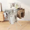 A white octopus-shaped drying rack with clothes hanging on it, placed indoors on a wooden floor next to a dresser. Produktbild-Vorschau