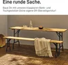 A wooden table and bench set with black metal legs, set up on a wooden tiled patio. Produktbild-Vorschau